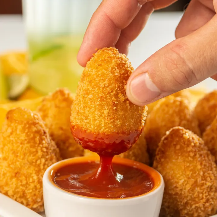 Coxinha de camarão mergulhada no molho